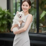 Chân dung thanh lịch của cô gái trẻ và chú chó Pomeranian ngoài quán cà phê hiện đại