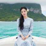 Hình ảnh chân dung sống động của cô gái trên thuyền giữa biển xanh và núi xanh