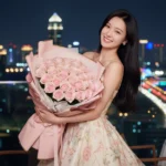 Cô gái châu Á xinh đẹp giữa ánh đèn thành phố đêm rực rỡ với bó hoa lãng mạn