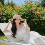 Cô gái tỏa sáng bên ghế trắng trong ánh nắng hè và hoa rực rỡ