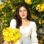 Chân dung cô gái trẻ bên cây hoa vàng rực rỡ trong trang phục vintage cá tính